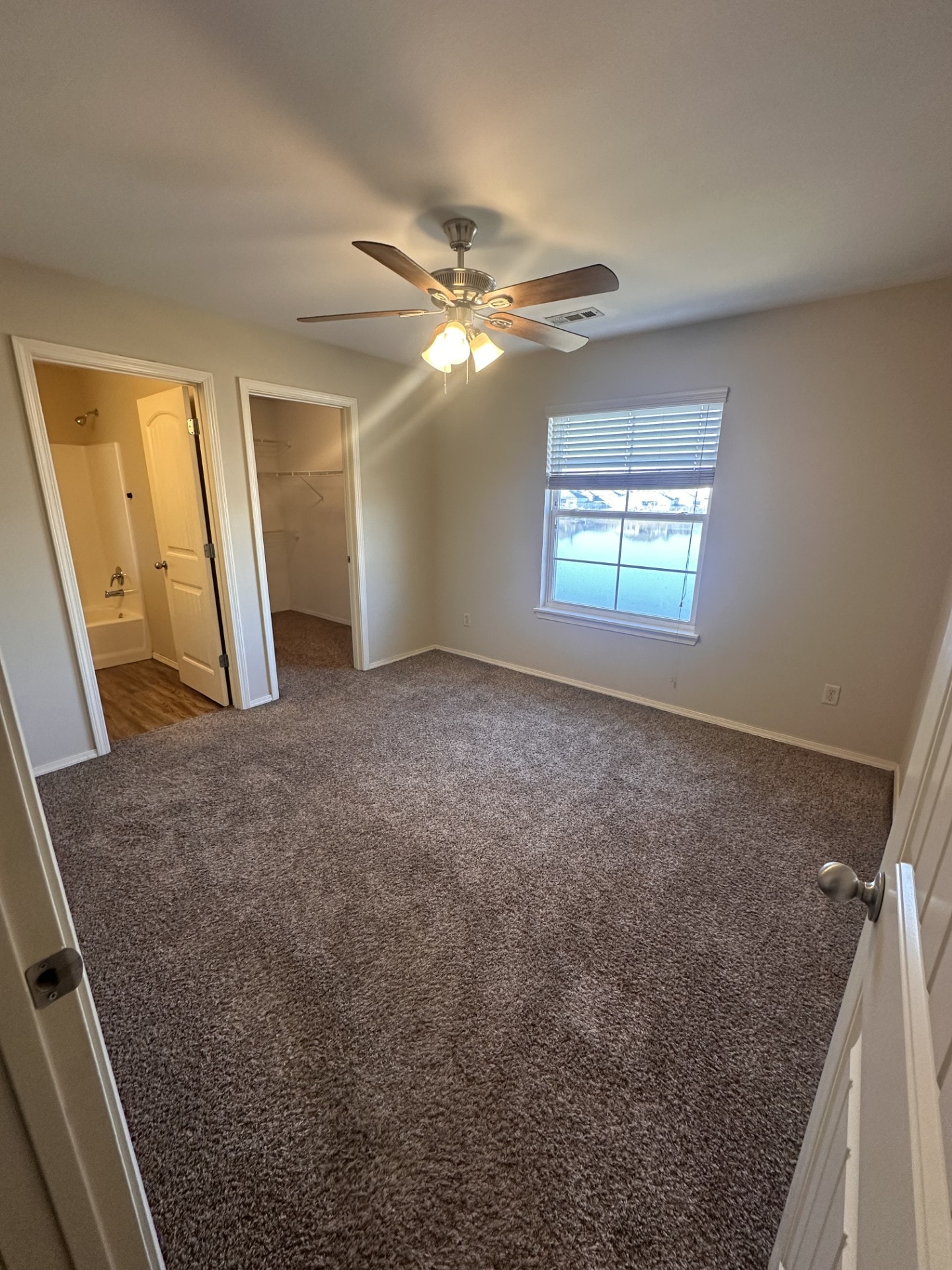 A room with a ceiling fan and carpeted floor.