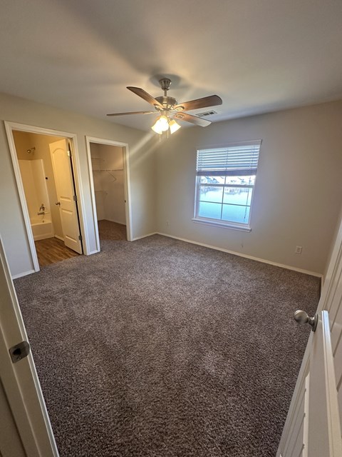 A room with a ceiling fan and carpeted floor.