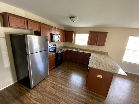 A kitchen with a refrigerator, oven, and cabinets.