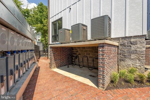 A building with a brick wall and a row of air conditioning units.