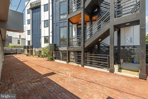 A modern building with a red brick walkway in front.