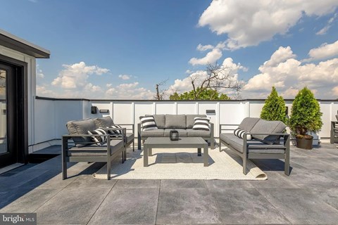 A patio with grey furniture and a white wall.