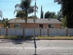 A house with a white fence and trees in front.