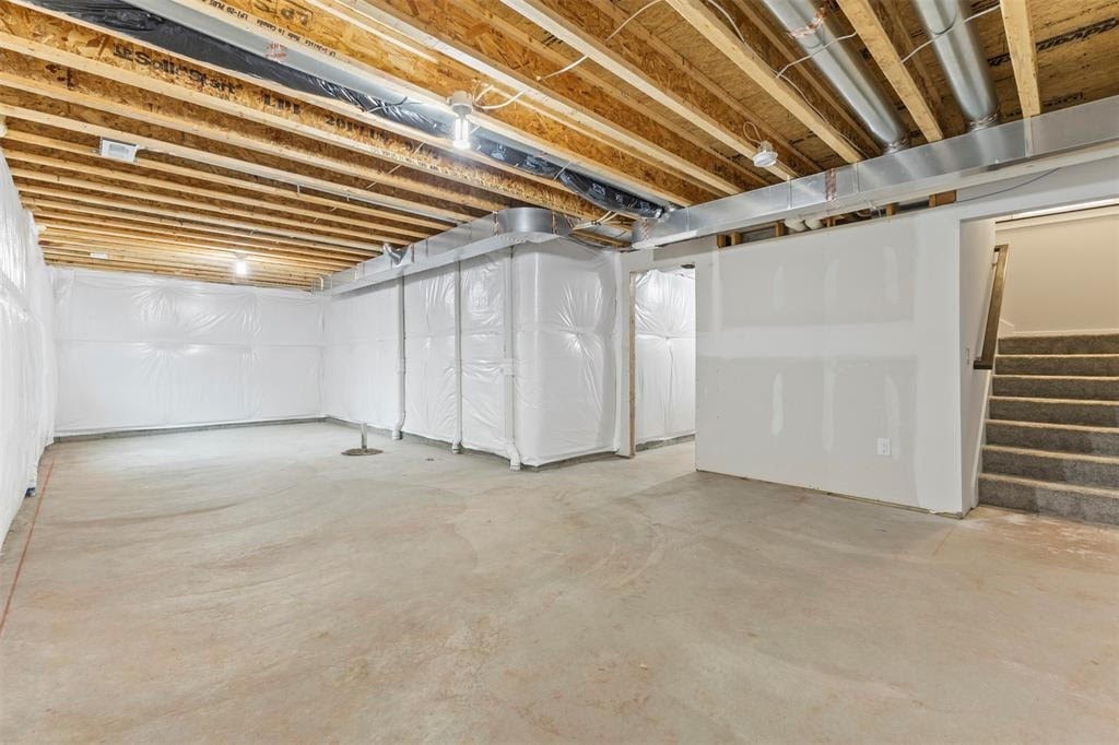 A room under construction with a concrete floor and a staircase on the right.