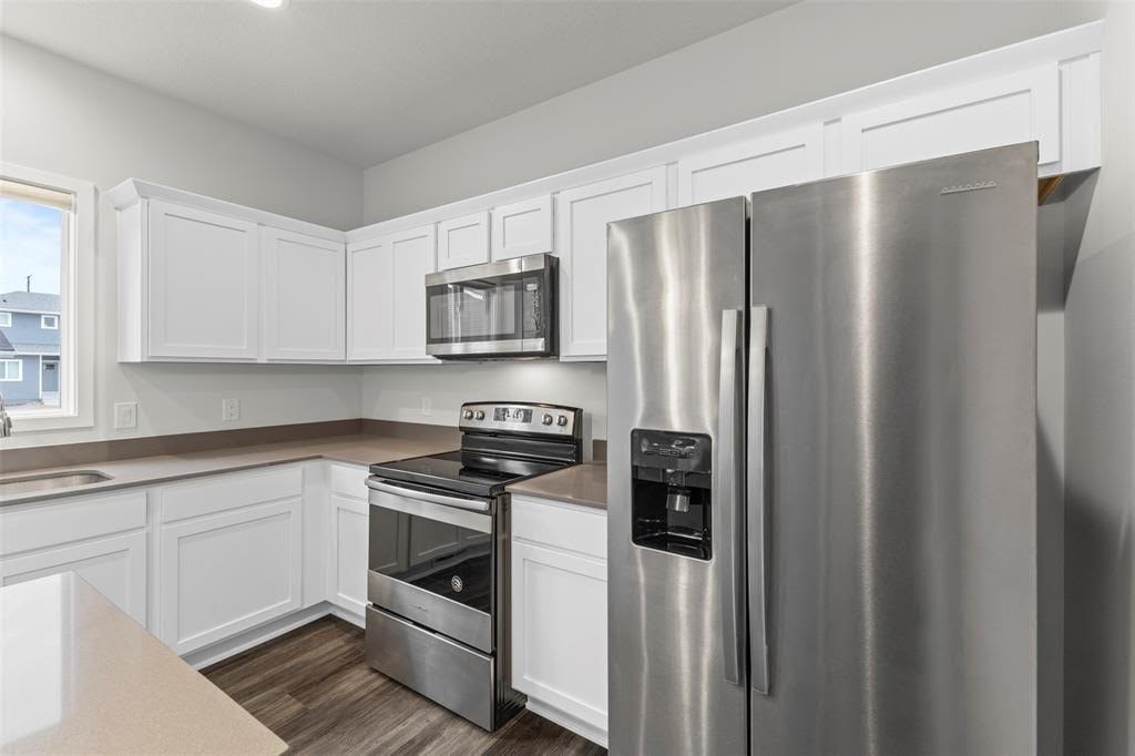 A modern kitchen with a stainless steel refrigerator, oven, and microwave.