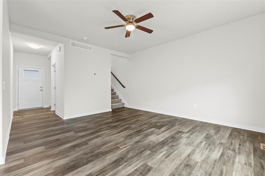 A room with a ceiling fan and wooden flooring.