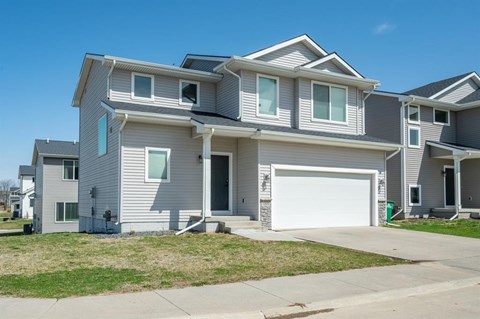 A large, modern house with a grey and white exterior and a white garage door.