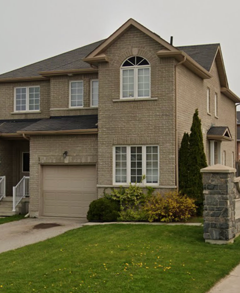 A house with a grey garage door and a stone pillar in front.