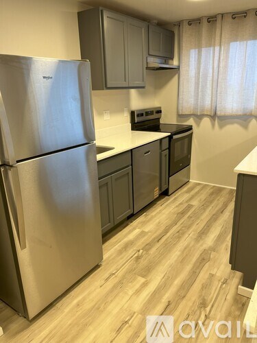 A kitchen with a stainless steel refrigerator and wooden flooring.