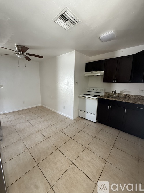 A kitchen with black cabinets and a granite countertop.