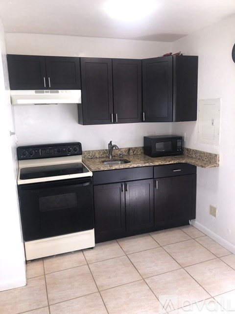 A kitchen with black cabinets and a granite countertop.