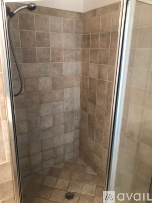 A shower stall with a glass door and tiled walls.
