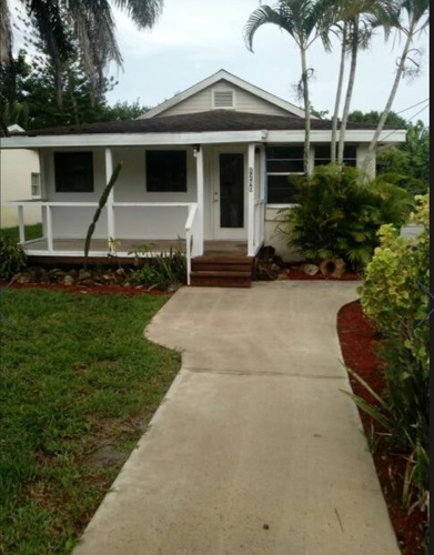 A white house with a porch and a concrete walkway in front.