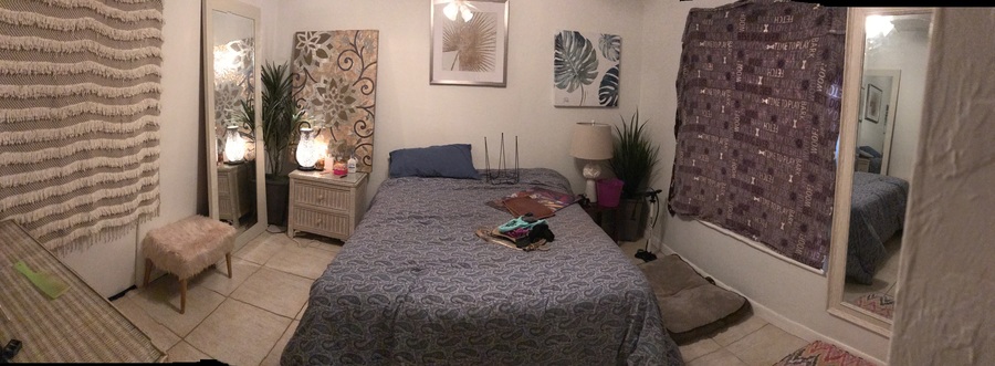 A bedroom with a bed, nightstand, and a wall hanging.