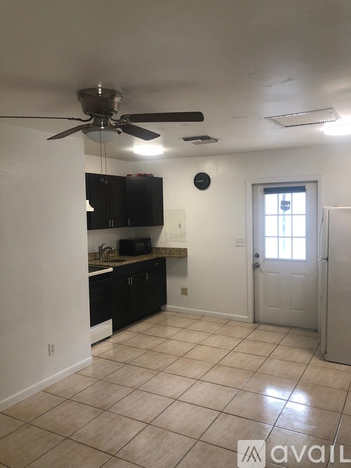 A kitchen with black cabinets and a ceiling fan.