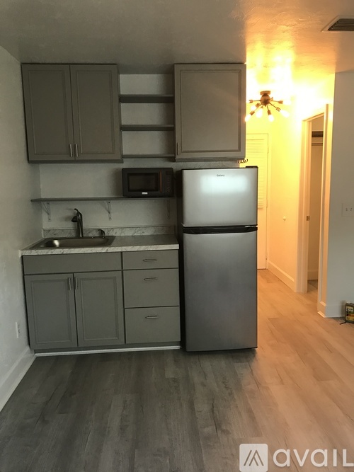 A kitchen with a refrigerator, microwave, and cabinets.