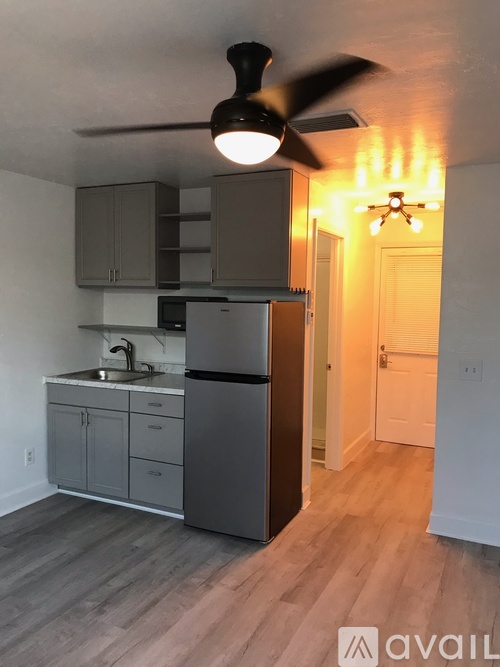 A kitchen with a fan and wooden floors.