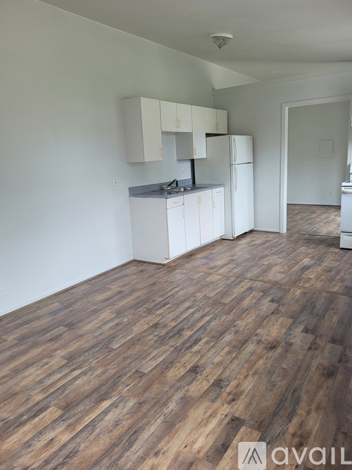 A kitchen with white cabinets and a wooden floor.