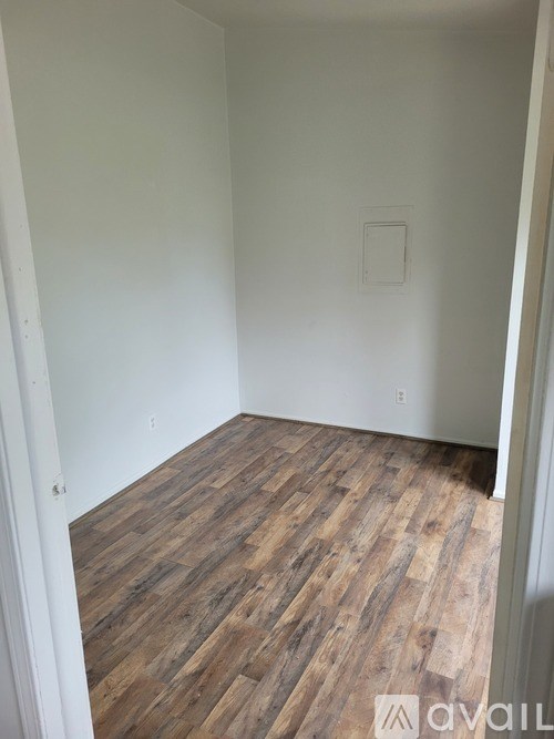 A room with wooden flooring and white walls.