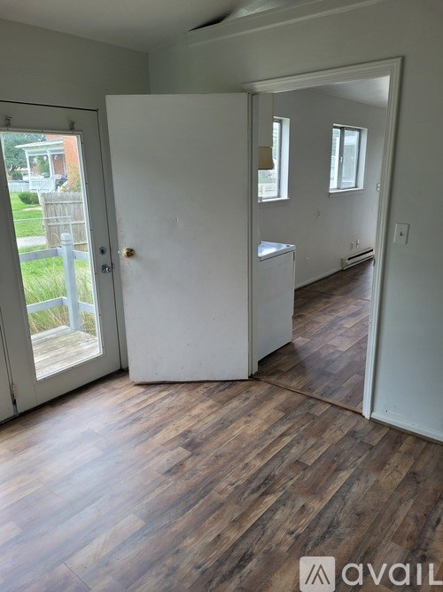 A room with a white door and wooden flooring.