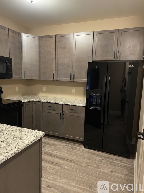 A kitchen with a black refrigerator and cabinets.