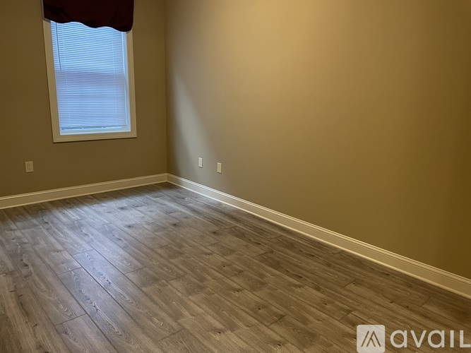 A room with wooden flooring and a window with blinds.