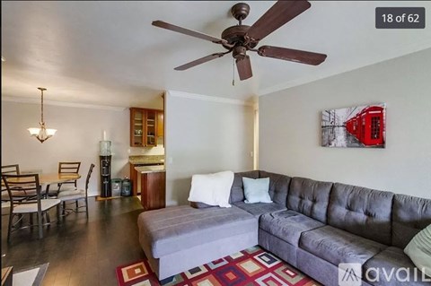 A living room with a grey couch and a ceiling fan.