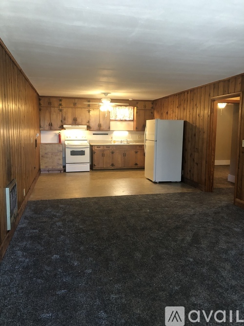 A kitchen with wooden walls and a white fridge.