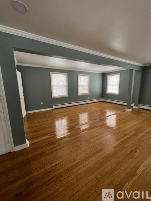 A room with wooden floors and three windows.