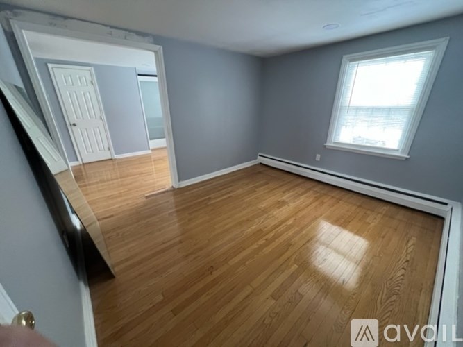 A room with wooden flooring and a window with white blinds.