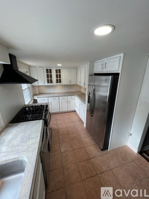 A kitchen with a black stove top and a refrigerator.