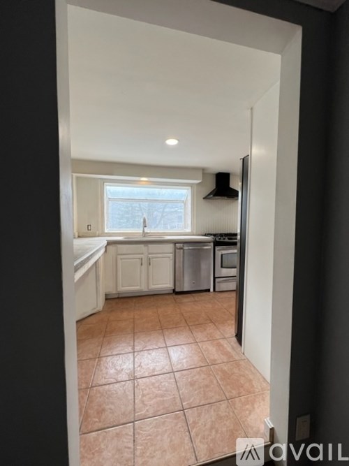 A kitchen with tile flooring and white cabinets.