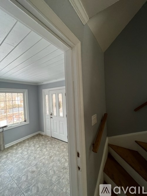 A hallway with a wooden staircase and a white door.