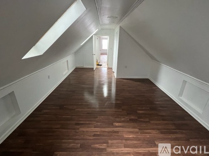 A long hallway with wood floors and white walls.