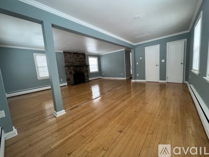 A spacious room with wooden floors and a fireplace.