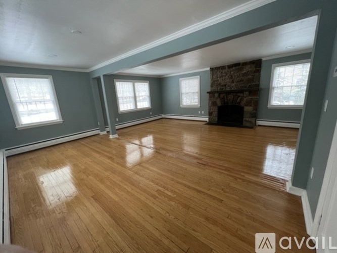 A room with wooden floors and a stone fireplace.