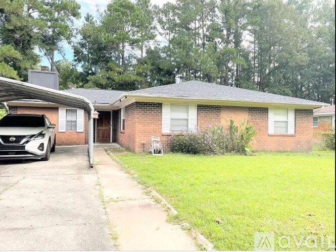 A white car is parked in front of a brick house.