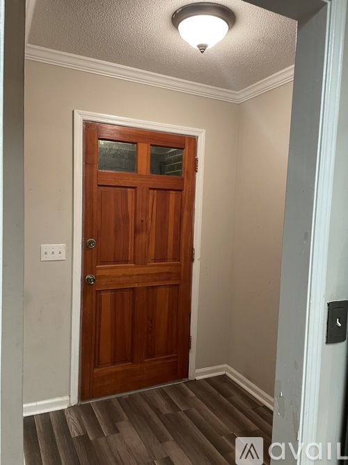 A wooden door with a glass panel is in a room with a light on the ceiling.