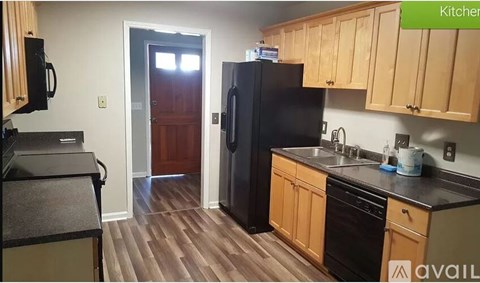 A kitchen with wooden cabinets and a black fridge.