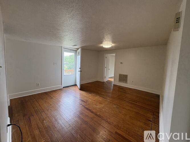 A room with wooden flooring and a window on the right side.