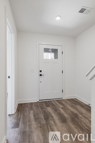 A room with a white door and wooden flooring.