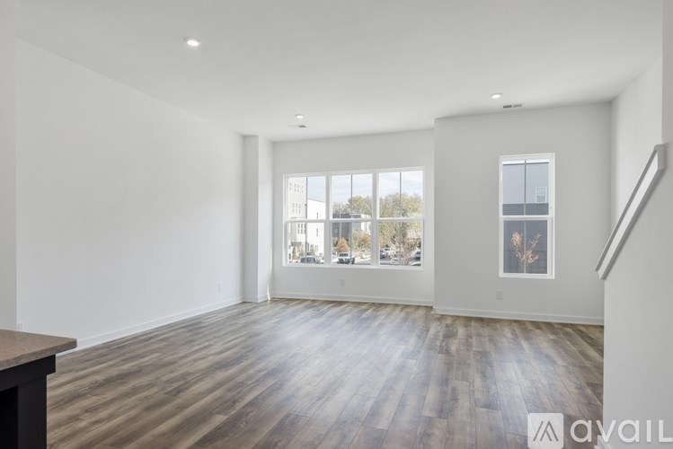 A spacious room with wooden floors and a large window overlooking a cityscape.