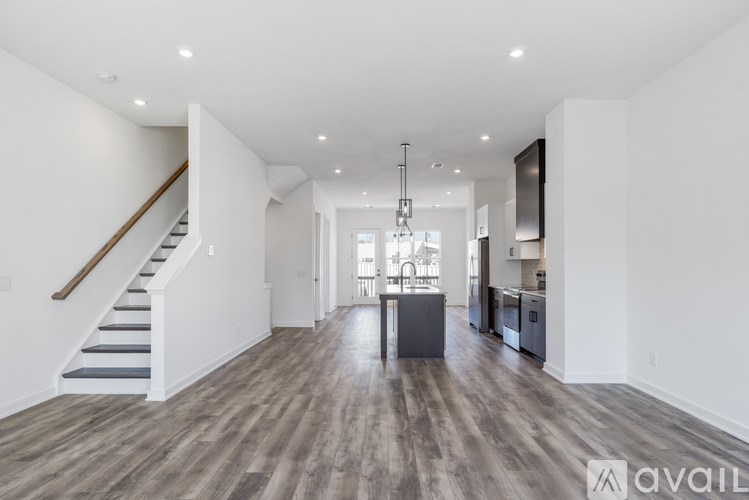 A spacious kitchen and living room with wooden floors and white walls.