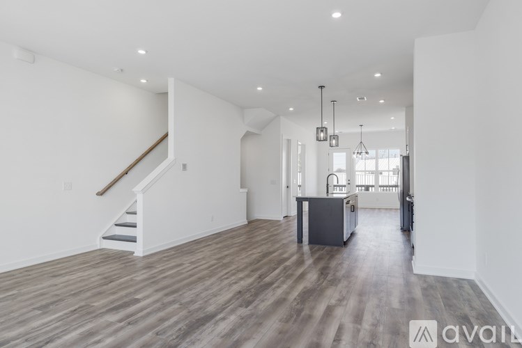 A spacious living room with wooden flooring and a staircase leading to the upper level.