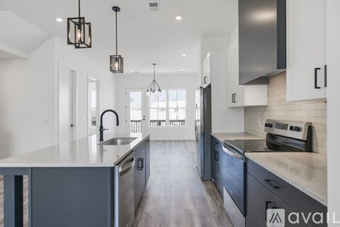A modern kitchen with dark grey cabinets and a wooden floor.