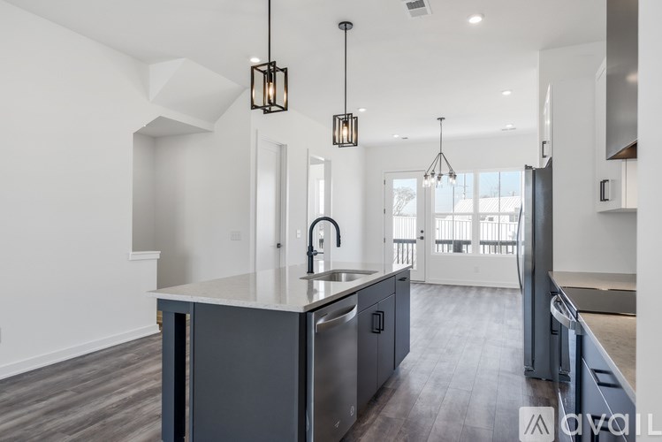 A modern kitchen with a large island and pendant lights.