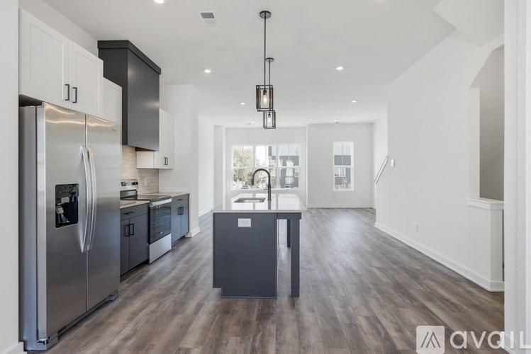 A modern kitchen with a refrigerator, cabinets, and a dining table.