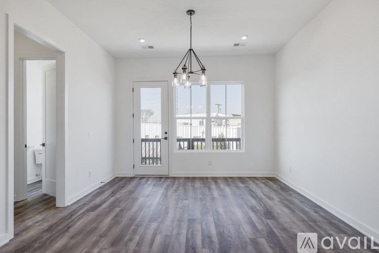 A spacious room with wooden floors and a chandelier hanging from the ceiling.