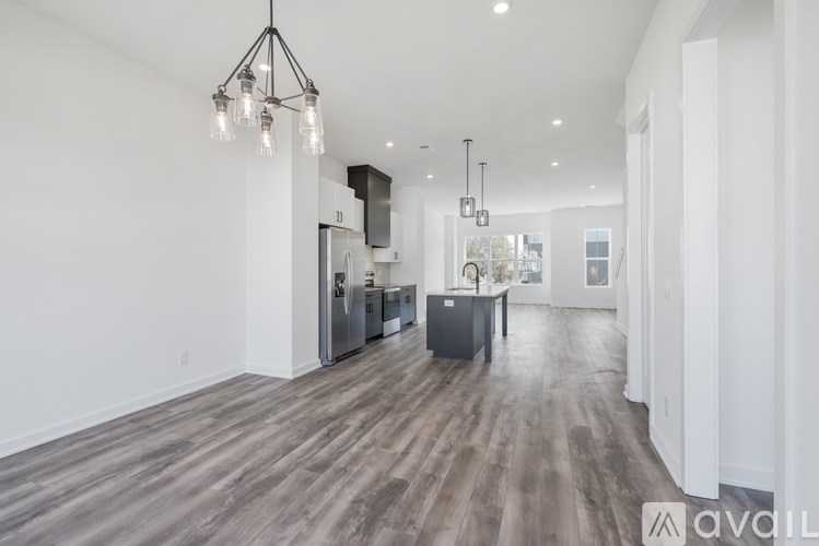 A modern kitchen with wooden floors and a black pendant light.