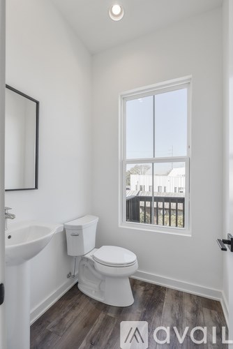 A bathroom with a toilet, sink, and window.